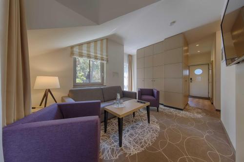 a living room with purple furniture and a table at Aquamaris Strandresidenz Rügen in Juliusruh