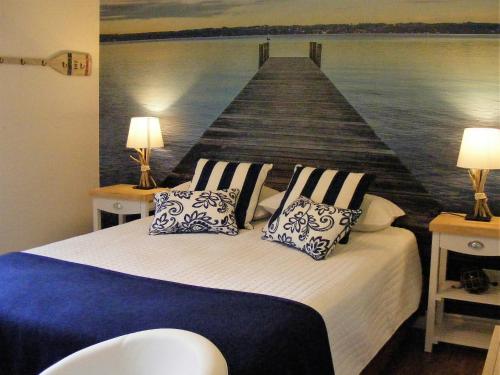 a bedroom with a bed with a painting of a pier at Gite L'Antre d'Eux in Sherbrooke