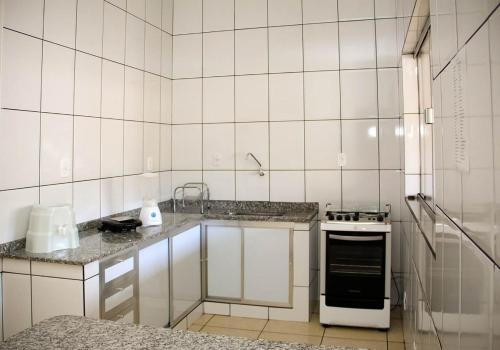 a white tiled kitchen with a sink and a stove at Chales do Velho Chico in Três Marias