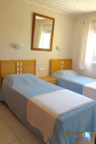 a hotel room with two beds and a mirror at Pl Les Bovetes Apt in Denia