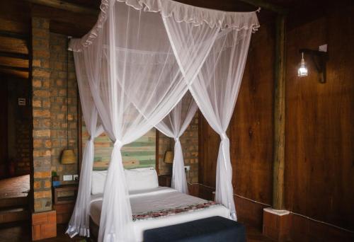 a bedroom with a canopy bed with white curtains at Buvi Lodge Limited in Entebbe