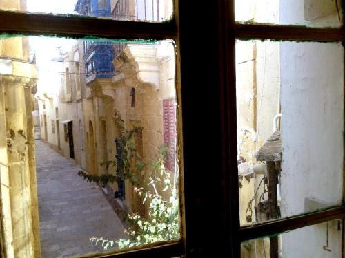 a view through a window of an alley at townhouse cospicua , ( 3 cities-valletta ) ferry in Cospicua