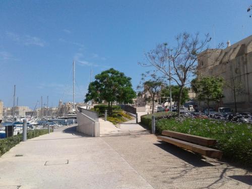 a bench on a sidewalk next to a harbor at townhouse cospicua , ( 3 cities-valletta ) ferry in Cospicua