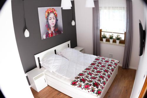 - une chambre avec un lit blanc et une photo d'une femme dans l'établissement Apartament Góralka, à Jaworki