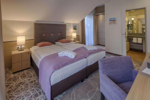 a bedroom with a large bed and a chair at Aquamaris Strandresidenz Rügen in Juliusruh