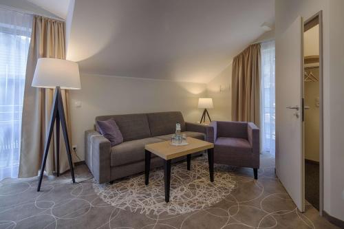 a living room with a couch and a table and a chair at Aquamaris Strandresidenz Rügen in Juliusruh