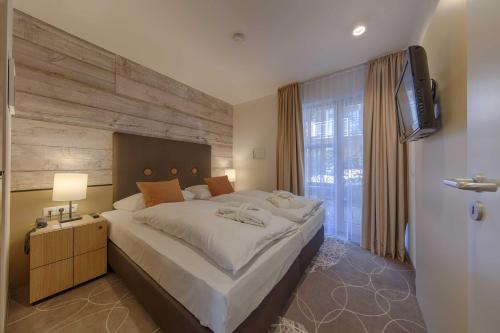 a bedroom with a large bed and a television at Aquamaris Strandresidenz Rügen in Juliusruh