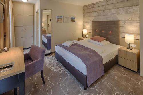 a bedroom with a bed and a desk and a chair at Aquamaris Strandresidenz Rügen in Juliusruh