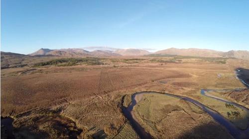 an aerial view of a river in a field with mountains at Kylemore Pass Hotel in Letterfrack