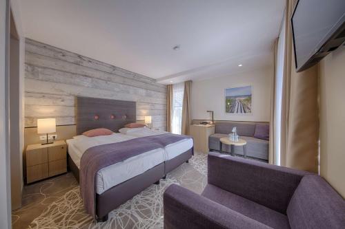 a bedroom with a large bed and a couch at Aquamaris Strandresidenz Rügen in Juliusruh