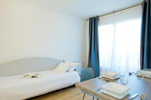 een slaapkamer met een bed, een tafel en een raam bij Brit Hotel Confort Lannion Centre Gare in Lannion