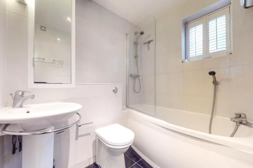 a white bathroom with a sink and a toilet and a tub at Panfield House in Braintree