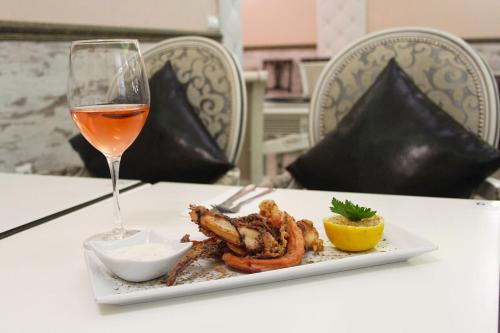 um prato de camarões e um copo de vinho sobre a mesa em Hotel Zeus em Pomorie