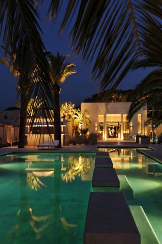 a swimming pool with palm trees in front of a building at Sezz Saint-Tropez in Saint-Tropez