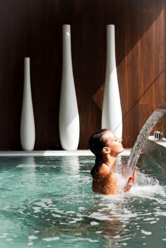 a woman is in a swimming pool pouring water at Sezz Saint-Tropez in Saint-Tropez