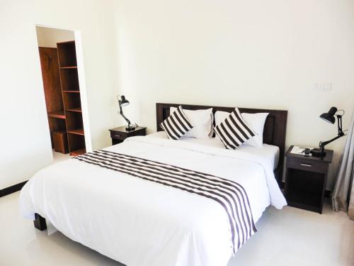 a white bed with black and white sheets and pillows at Plawa Bali Guest House in Canggu