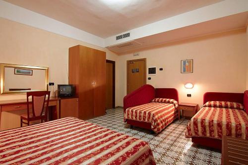 a hotel room with two beds and a desk at Hotel Gaggiano in San Giovanni Rotondo