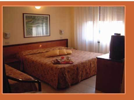 Hotel Moderno في ريميني: غرفة نوم بسرير وتلفزيون وطاولة