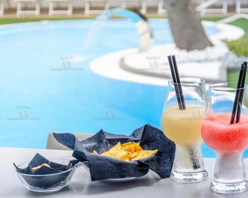 a drink and chips on a table next to a pool at Hotel Bellavista in Marina di Varcaturo