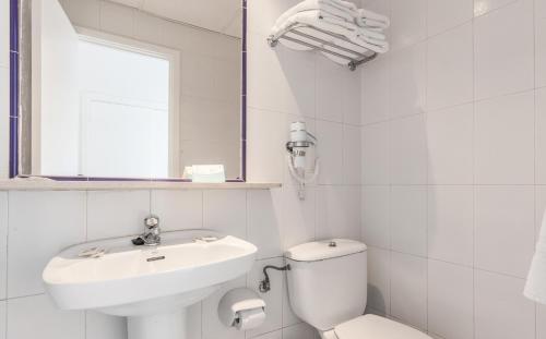 La salle de bains blanche est pourvue d'un lavabo et de toilettes. dans l'établissement BLUESEA Costa Verde, à El Arenal