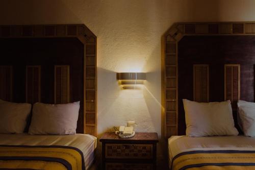 a hotel room with two beds and a lamp at Hotel Ambassador Mérida in Mérida