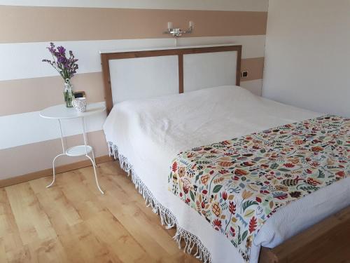 B&B del Lago في إيسبرا: غرفة نوم بسرير وطاولة مع إناء من الزهور