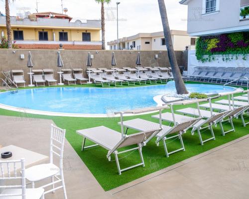 a swimming pool with lounge chairs and a table at Hotel Bellavista in Marina di Varcaturo