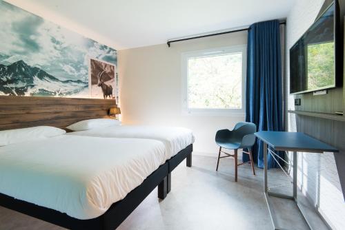 a hotel room with two beds and a desk and a window at Ibis Styles Sallanches Pays du Mont-Blanc in Sallanches