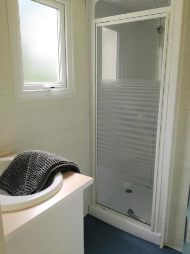une douche en verre dans une salle de bain avec un lavabo dans l'établissement camping Le Kermadec, à Ambon