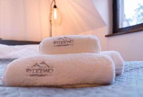 a pile of towels sitting on top of a bed at Apartamenty Rydzewo in Rydzewo