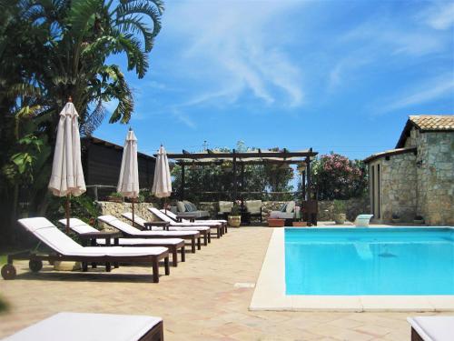 a row of lounge chairs with umbrellas and a pool at B&B Villa Giusy in Siracusa