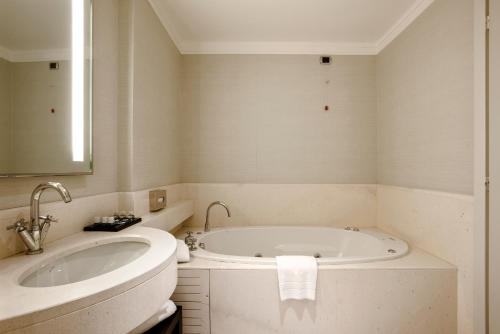 a white bathroom with a tub and a sink at FlyOn Hotel & Conference Center in Bologna