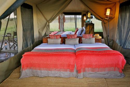 a bed in a tent with red pillows at Pumzika Luxury Safari Camp in Banagi