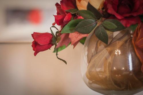a glass vase with red roses in it at Case Vacanze Al Duomo in Licata
