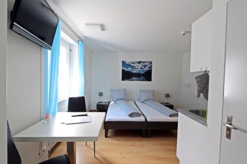 Habitación pequeña con cama, escritorio y TV. en b&b River Inn en St. Moritz