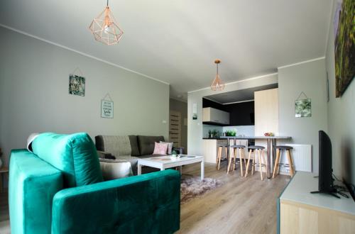 a living room with a blue couch and a kitchen at Apartament u stóp Śnieżki in Karpacz