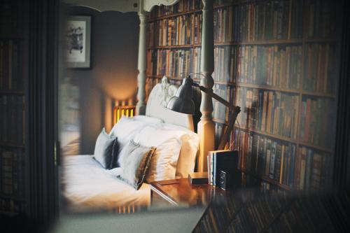 a bedroom with a bed with bookshelves and a lamp at Rum Doodle, Windermere B&B in Windermere