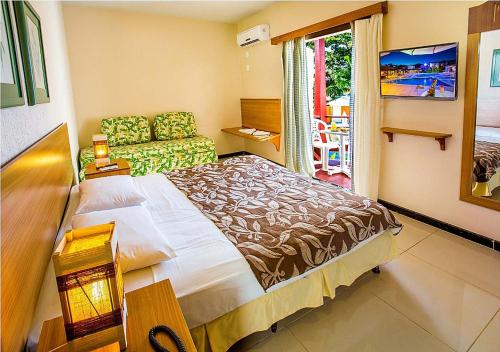 a bedroom with a large bed and a couch at Happy Hotel Girassol in Porto Seguro