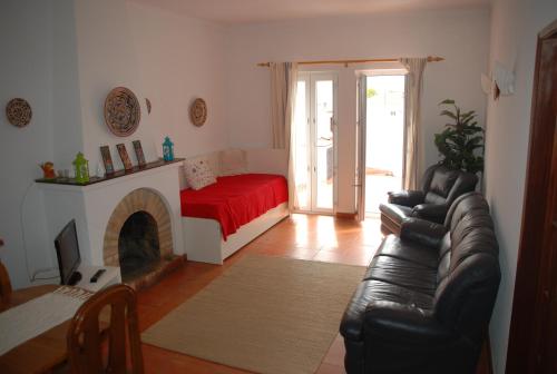 a living room with a leather couch and a bed at Casa Sobral in Vila Nova de Milfontes