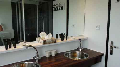 La salle de bains est pourvue de 2 lavabos et d'un grand miroir. dans l'établissement Noordwester 45, à Den Burg