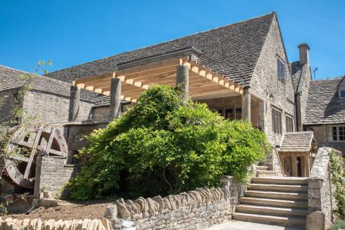 an old stone house with a wooden pergola at The Frogmill Hotel in Cheltenham