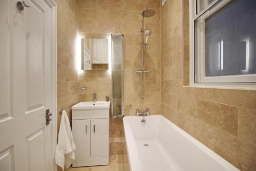 a bathroom with a tub and a sink and a shower at Macatsim Seaview Sunset in Margate