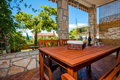 a wooden table on a patio with a bottle of wine at Monte Holiday Home with Jacuzzi in Rovinj