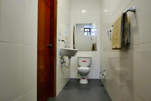a white bathroom with a toilet and a sink at Hotel Norte in Cuenca