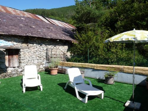 two lawn chairs and an umbrella on the grass at Chalet Le Bois Noir in Valdeblore