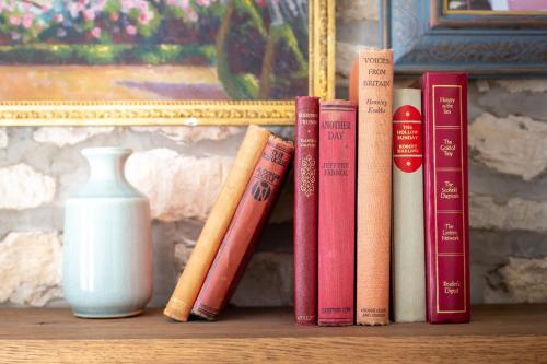 a row of books on a shelf next to a vase at The Frogmill Hotel in Cheltenham