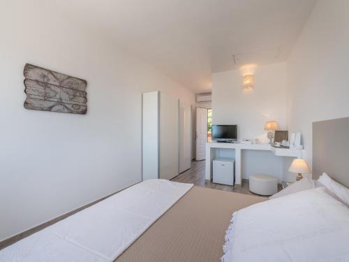 ein weißes Schlafzimmer mit einem Bett und einem Schreibtisch in der Unterkunft Panoramic Studio Carloforte in Carloforte