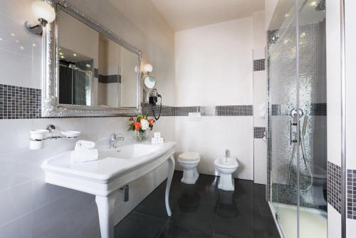 a bathroom with a sink and a toilet and a mirror at Hotel Corsignano in Pienza