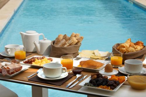 a breakfast table with breakfast foods and drinks and a pool at Le Mas de Cocagne in Saintes-Maries-de-la-Mer