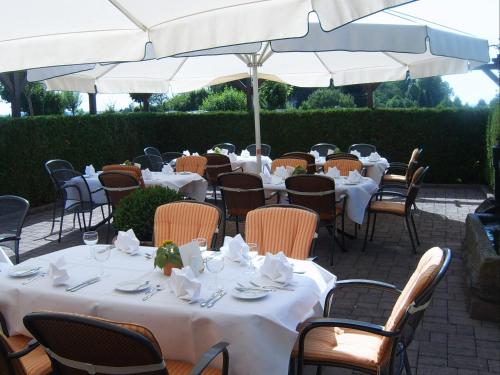 a group of tables and chairs with white tables and white umbrellas at Hotel Drei Konige in Schramberg